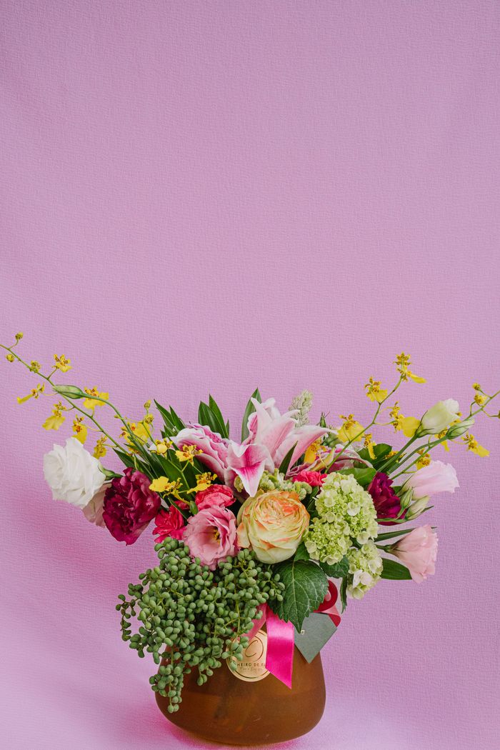 services-02 A colorful floral arrangement featuring roses and lilies against a pink backdrop.