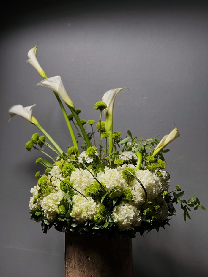 Chic floral arrangement featuring white calla lilies and green accents.
