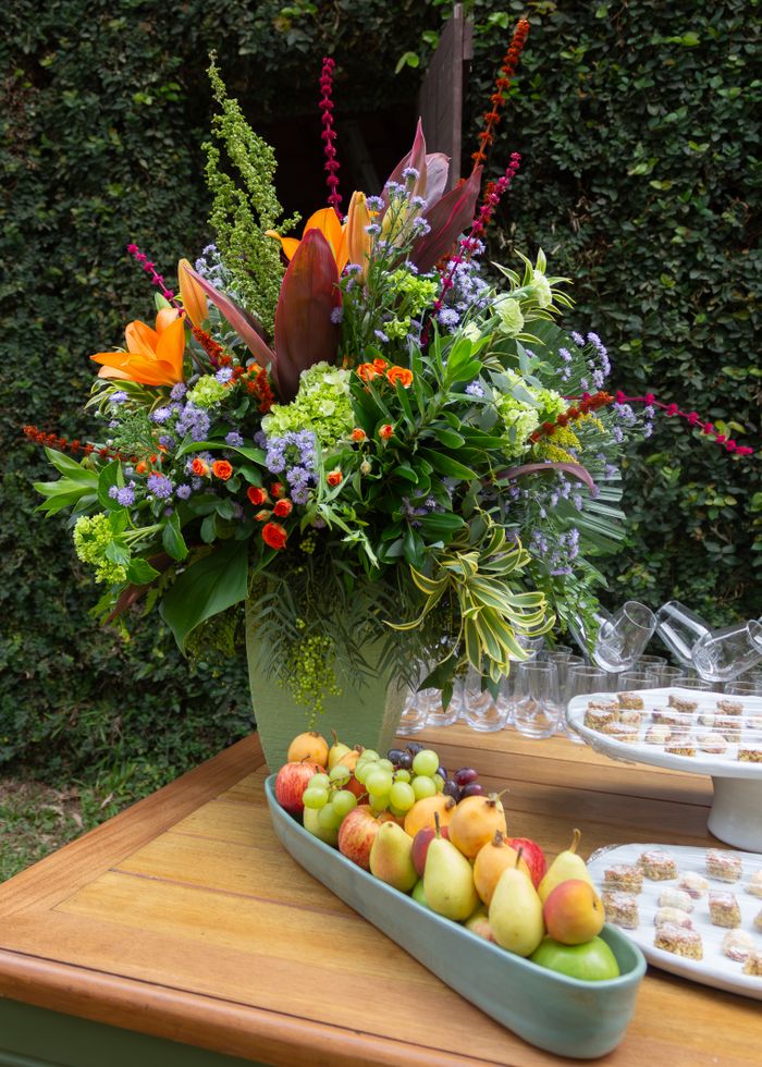 services-01 A colorful floral bouquet with fresh fruits on a wooden table outdoors.
