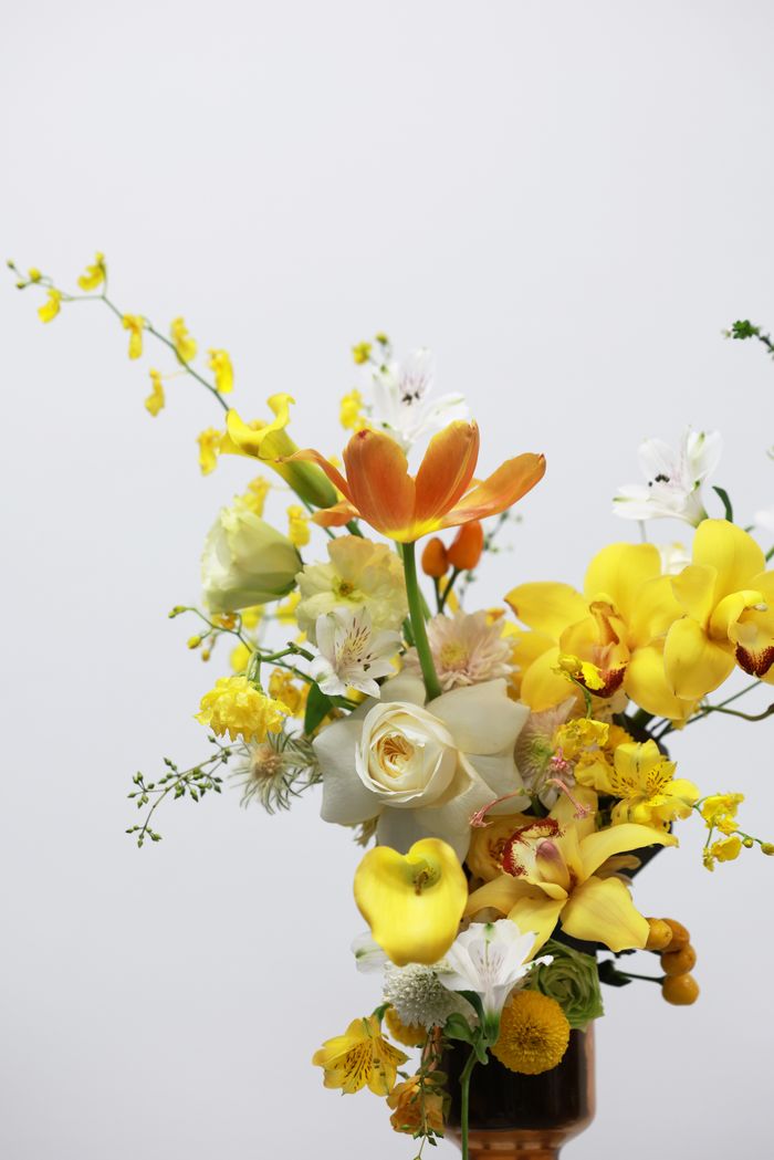 services-03 A vivid arrangement of yellow and orange flowers in a bouquet set against a white background, showcasing spring's beauty.